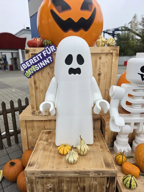 A brick-built ghost minifigure taller than a child, in front of a giant carved pumpkin, with a sign reading "Bereit für BOOsinn?"