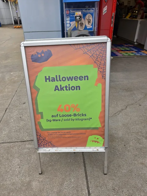A sign in front of the shop reading "Halloween Aktion: 40% auf Loose-Bricks (kg-Ware / sold by kilogram)", only while stocks last, items with individual prices in the display case excluded