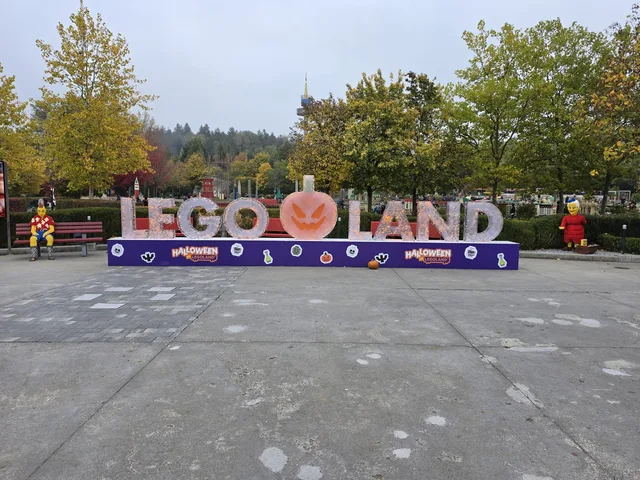 The LEGOLAND lettering on the square inside the park, with a carved pumpkin standing between LEGO and LAND and Halloween banners along the base
