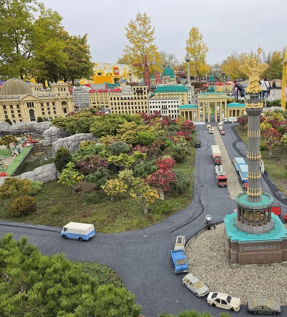 The Berlin section of Miniland: the golden Victory Column on a roundabout with brick-built cars, a road leading to the Brandenburg Gate and the Reichstag, and autumn shrubs everywhere