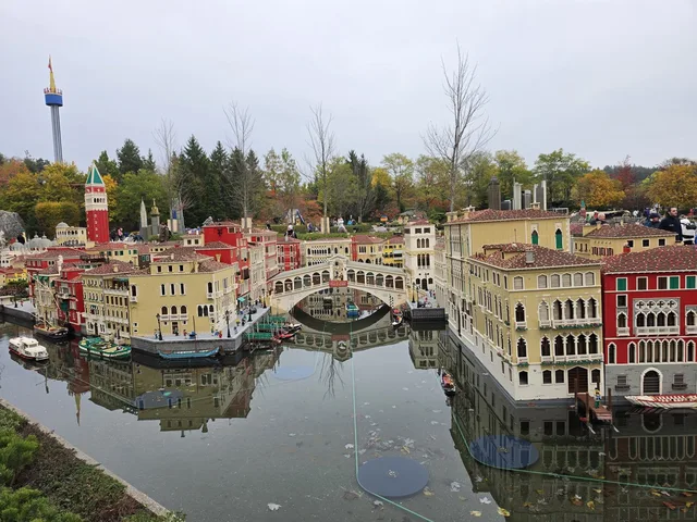 The Venice section of Miniland: the Rialto Bridge over a canal lined with red and ochre palazzi, reflected in the still water, with the Campanile in the background