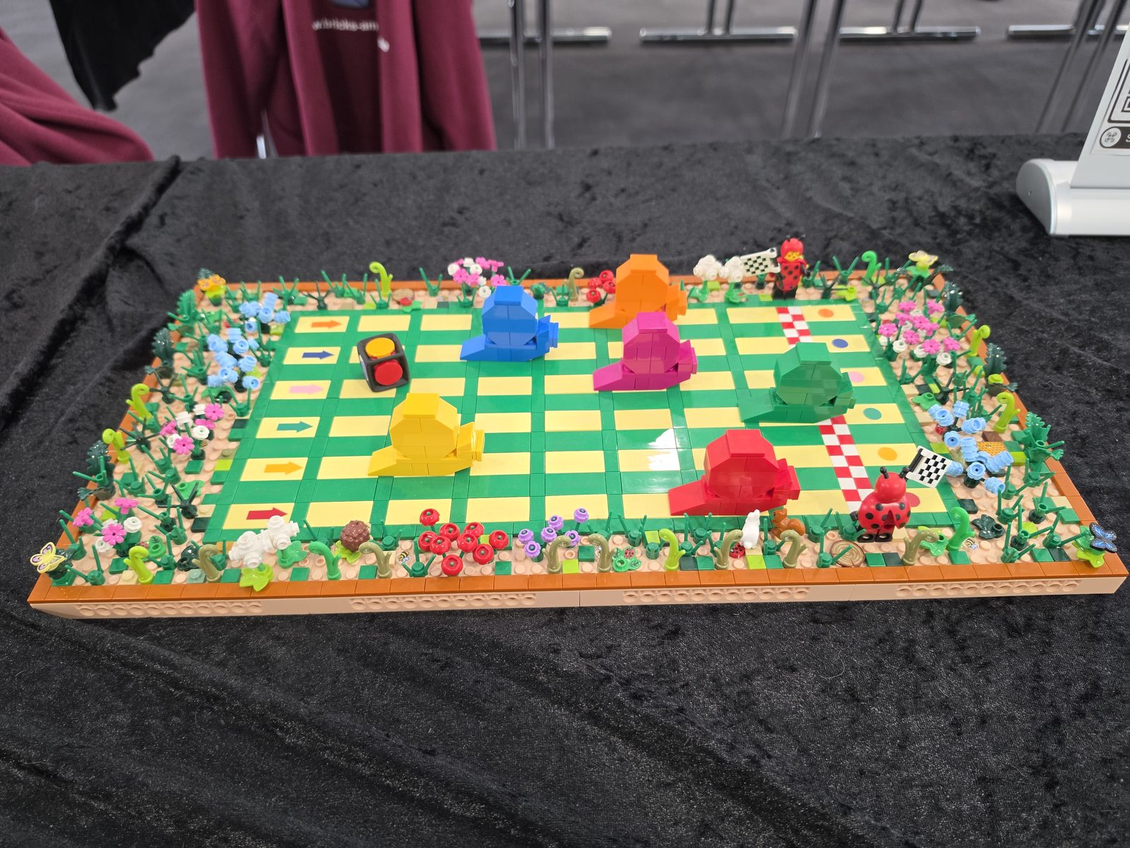 A Mensch-ärgere-dich-nicht board built entirely from LEGO bricks, with a border of flowers